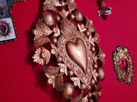 A wall with heart decorations and artwork at Frida's Cottage in Whitby