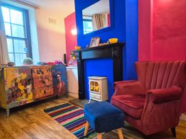 A living room with a red armchair and decorative chest of drawers at Frida's Cottage in Whitby