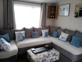 A living room with a sofa and decorative cushions at 48 Woodland View Lymington