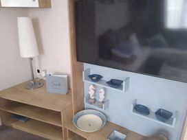 A living room with a lamp and television at 48 Woodland View Lymington