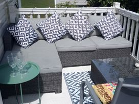 An outdoor seating area with a sofa, coffee table, and glasses at 48 Woodland View in Lymington