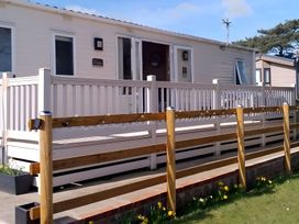 A cabin with a deck and railing at 48 Woodland View in Lymington