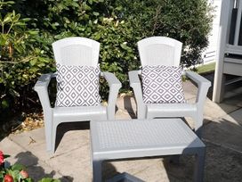 Two gray chairs with cushions and a table at 48 Woodland View in Lymington