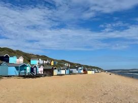 Beach with colorful beach huts and sand at 48 Woodland View Lymington