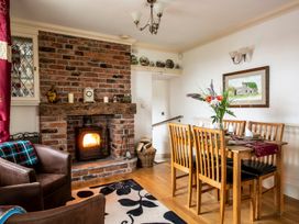 A dining room with a fireplace and a wooden table at Bank House Cottage in Lancaster