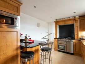 A kitchen with a stove and bar stools at Bank House Cottage in Lancaster