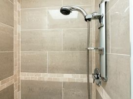 A shower with a chrome showerhead and tiled walls at Bank House Cottage Lancaster