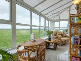 A conservatory with a rattan sofa and table at Bank House Cottage in Lancaster