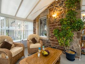 A conservatory with chairs and a table at Bank House Cottage in Lancaster