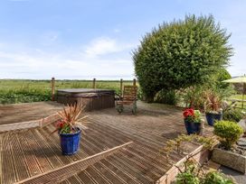 A deck with a hot tub and flower pots at Bank House Cottage, Glasson Dock