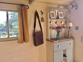 A kitchen with a cupboard and a vase of flowers at Cosy Shepherd’s Hut in Longhope