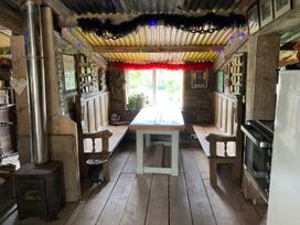 A dining room with a wooden table and benches at Cosy Shepherd’s Hut in Longhope