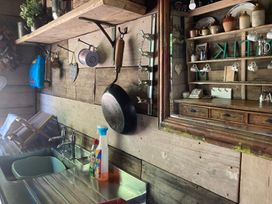 A kitchen with a sink, shelf, and mirror at Cosy Shepherd’s Hut in Longhope