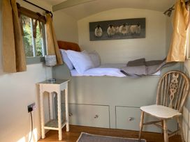 A bedroom with a bed and chair at Cosy Shepherd’s Hut Longhope