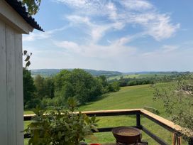 A view of a green field and hills from a balcony at Cosy Shepherd’s Hut Longhope