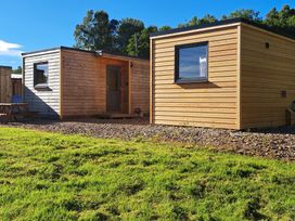 Two wooden cabins with a gravel area and grass at The Posh Bothy 2 Roy Bridge