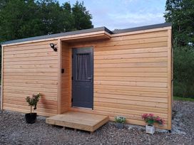 An outdoor view of a wooden building with a door and window at The Posh Bothy 2 in Roy Bridge