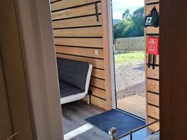 A room with a sofa and door to the outdoor area at The Posh Bothy 2 in Roy Bridge