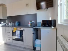 A kitchen with a sink, oven, kettle, toaster, microwave, and fridge at The Posh Bothy 2 Roy Bridge