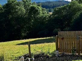 A fenced area with a wooden gate and stuffed animals at The Posh Bothy 2 in Roy Bridge