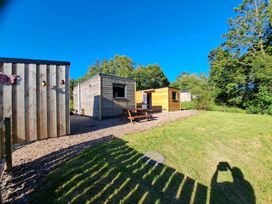 An outdoor area with wooden cabins and a picnic table at The Posh Bothy 2 in Roy Bridge
