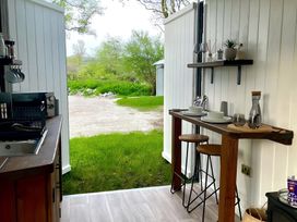 A kitchen with a wooden table and stools at Trethowels Hidden Huts in St. Austell