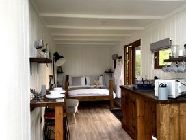 A bedroom with a bed and dining area at Trethowels Hidden Huts in St. Austell