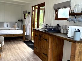 A studio with a bed, kitchen cabinet and microwave at Trethowels Hidden Huts in St. Austell
