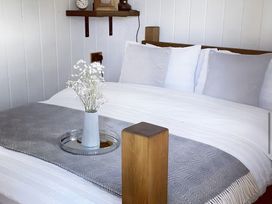 A bedroom with a bed and a vase of flowers at Trethowels Hidden Huts in St. Austell