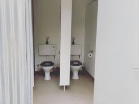 A bathroom with two toilets and a partition at Trethowels Hidden Huts in St. Austell