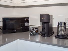 A kitchen with a microwave, coffee maker, and milk frother at Pityme-Not in Wadebridge