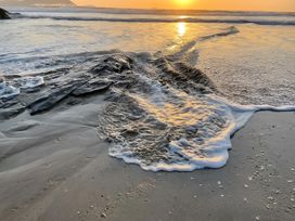A beach with waves and rocks at Pityme-Not in Wadebridge