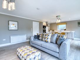 A living room with a sofa and kitchen area at Pinemarten Lodge Crianlarich