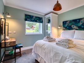 A bedroom with a bed, desk and window at Pinemarten Lodge in Crianlarich