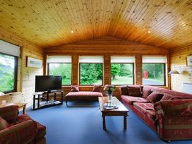 A living room with a television and sofa at Buzzard Lodge in Crianlarich