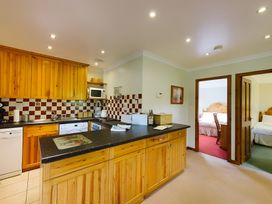 A kitchen with wooden cabinets and appliances at Buzzard Lodge in Crianlarich