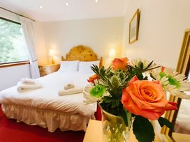 A bedroom with a bed and flowers at Buzzard Lodge in Crianlarich