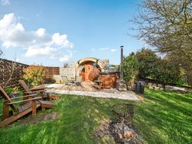 An outdoor garden with a hot tub, wooden chairs and fire pit at Cosy Escape in Minster On Sea