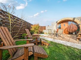 A garden with wooden chairs and a dining table at Cosy Escape in Minster On Sea