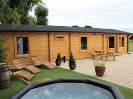 An outdoor area with a cabin, hot tub, and wooden furniture at Cotswold Nights Away in Evesham