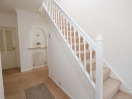 A hallway with a staircase and a shelf at 15 Coombe Avenue