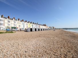 A beach view with houses and beach huts at 15 Coombe Avenue