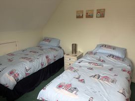 A bedroom with two beds and nightstand at Tudor Rose in Weymouth