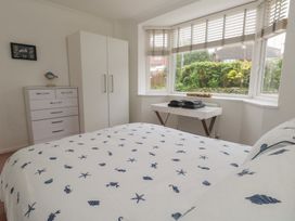 A bedroom with a bed, wardrobe, and dresser at Tudor Rose in Weymouth