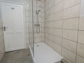 A shower area with tiled walls and a door at Tudor Rose in Weymouth