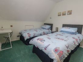 A bedroom with two beds and a desk at Tudor Rose in Weymouth