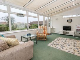 A conservatory with a sofa and coffee table at Tudor Rose in Weymouth