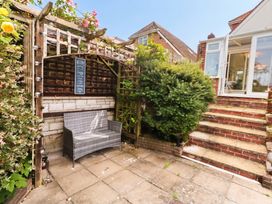 A garden with a bench and an archway at Tudor Rose in Weymouth