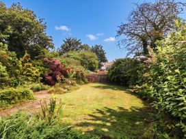 A garden with grass and trees at Tudor Rose in Weymouth