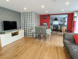 A living room with a television, dining table and kitchen at Ty Llyn in Brynteg near Benllech